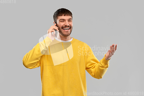 Image of happy smiling young man calling on smartphone