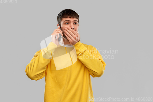 Image of shocked young man calling on smartphone