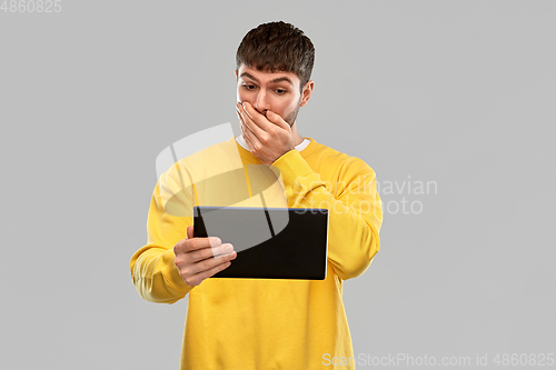 Image of shocked young man with tablet pc computer