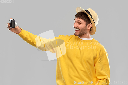 Image of happy man in straw hat with vintage film camera