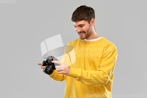 Image of smiling young man with digital camera