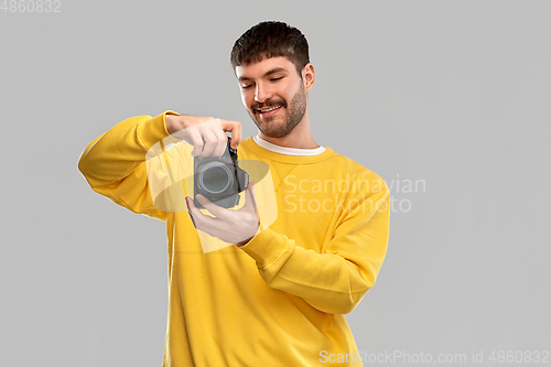 Image of smiling young man with digital camera