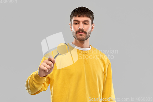 Image of man in yellow sweatshirt with magnifier