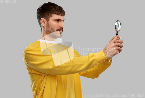 Image of man in yellow sweatshirt with magnifier