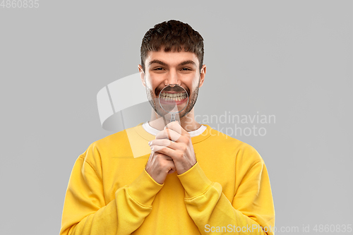 Image of smiling man with magnifier showing his teeth