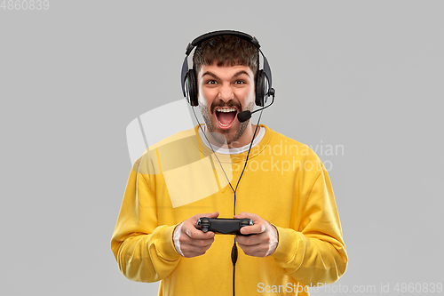 Image of man with headset and gamepad playing video game