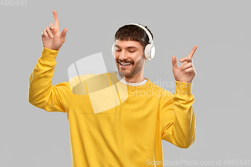 Image of happy smiling young man in headphones dancing