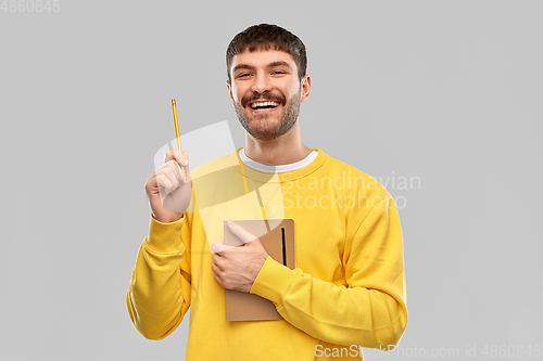 Image of happy man in yellow sweater with diary and pencil