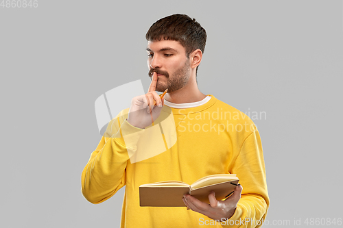 Image of thinking man with diary and pencil