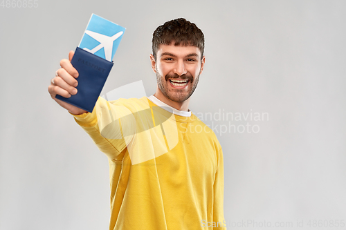 Image of smiling young man with air ticket and passport