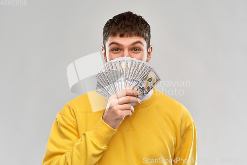 Image of happy young man in yellow sweatshirt with money