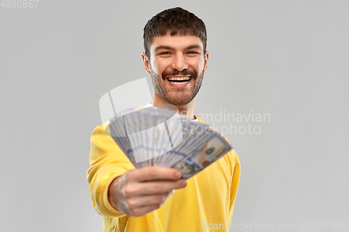 Image of smiling young man in yellow sweatshirt with money