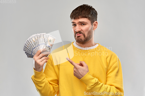 Image of displeased man in sweatshirt with dollar money