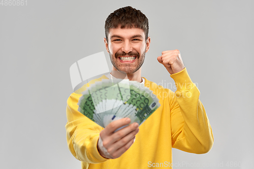 Image of happy young man with money celebrating success