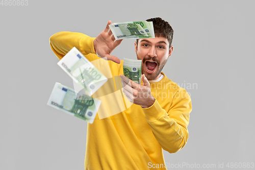 Image of happy man in yellow sweatshirt pouring money