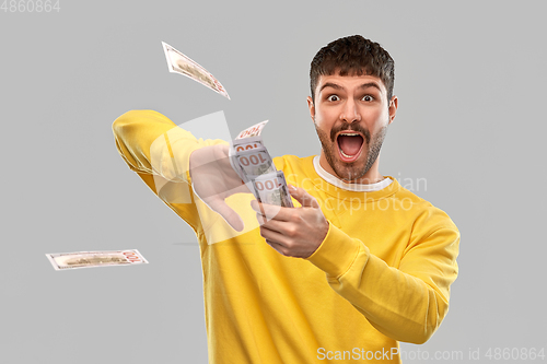 Image of happy man in yellow sweatshirt throwing money