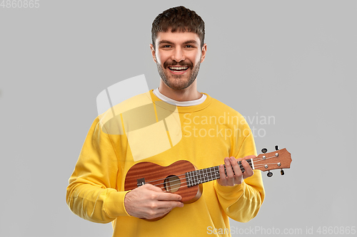 Image of smiling young man playing ukulele guitar