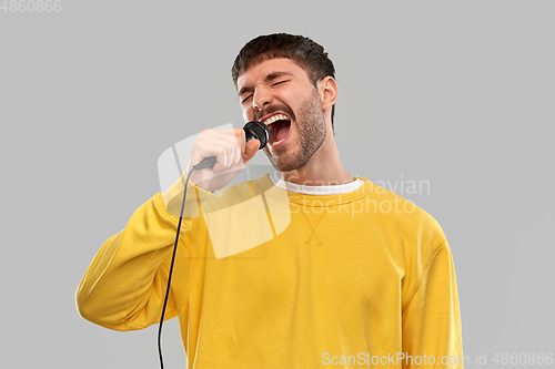 Image of man in yellow sweatshirt with microphone singing