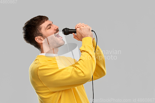 Image of man in yellow sweatshirt with microphone singing