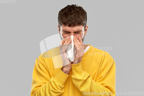 Image of man with paper napkin blowing nose