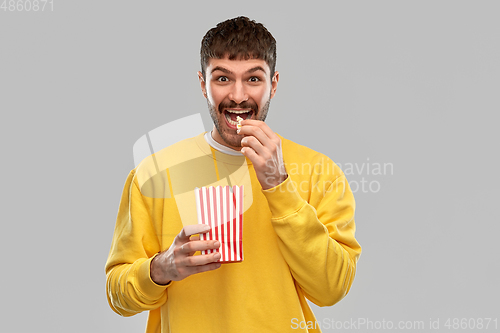 Image of smiling man in yellow sweatshirt eating popcorn