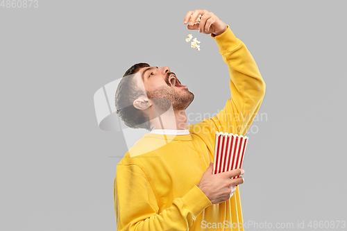 Image of man in yellow sweatshirt eating popcorn