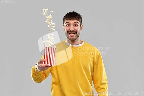 Image of man in yellow sweatshirt playing with popcorn