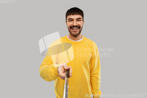 Image of happy young man taking picture with selfie stick