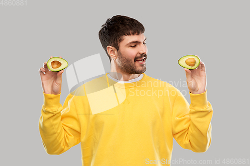 Image of happy young man in yellow sweatshirt with avocado