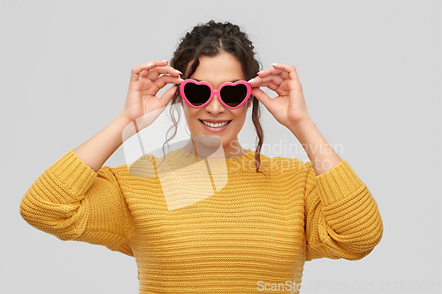 Image of smiling young woman in heart-shaped sunglasses