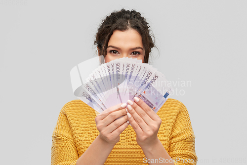 Image of young woman covering her face with euro money