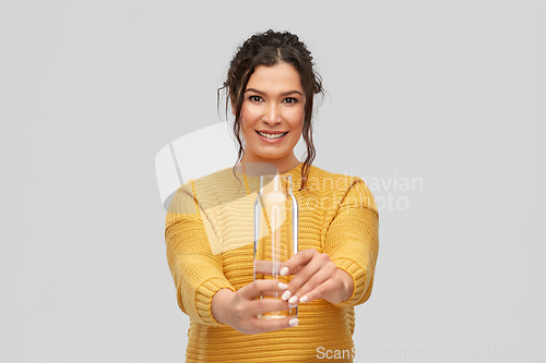 Image of smiling young woman with water in glass bottle