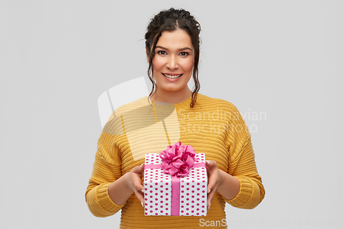 Image of smiling young woman holding gift box