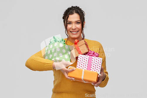 Image of smiling young woman holding gift boxes