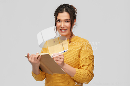 Image of happy young woman writing to diary or notebook