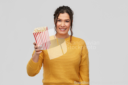 Image of happy smiling young woman with bucket of popcorn