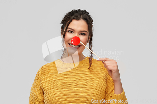 Image of happy smiling young woman with red clown nose