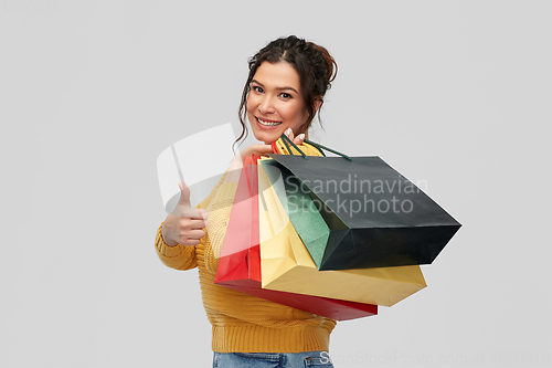 Image of smiling woman with shopping bags showing thumbs up