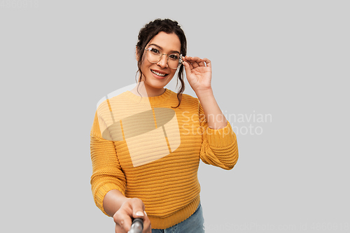 Image of smiling woman taking picture with selfie stick