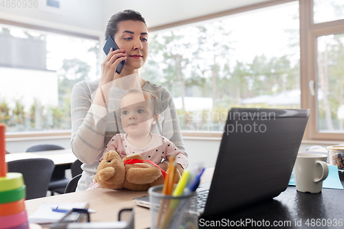 Image of mother with baby working on laptop at home office