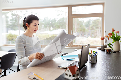 Image of young woman with blueprint working at home office