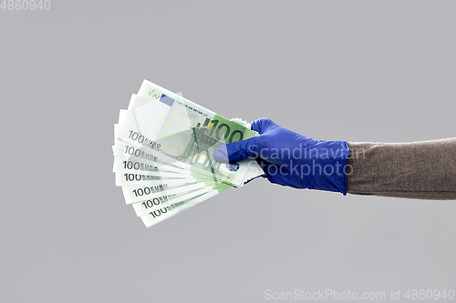 Image of close up of hand in medical glove with money