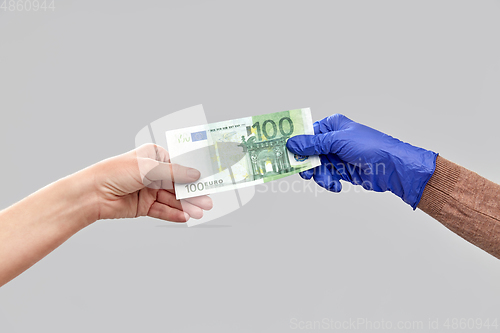 Image of close up of hand in medical glove giving money