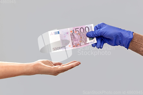 Image of close up of hand in medical glove giving money