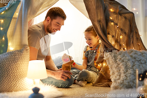 Image of happy family playing with toy in kids tent at home