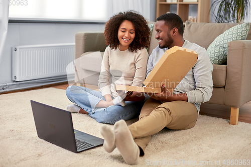 Image of happy african american couple eating pizza at home