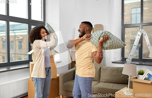 Image of happy couple having pillow fight at new home