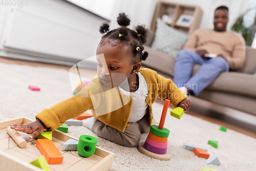 Image of african baby girl playing with toy blocks at home