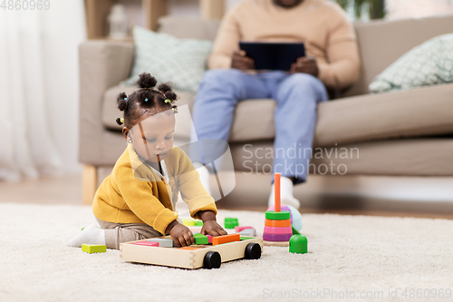 Image of african baby girl playing with toy blocks at home