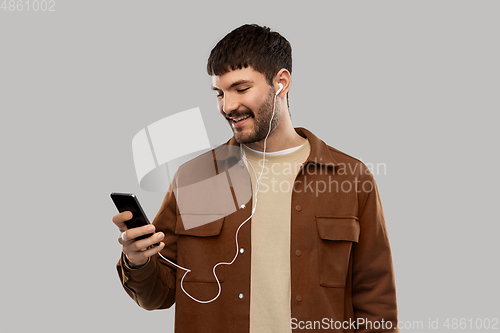 Image of smiling young man with earphones and smartphone